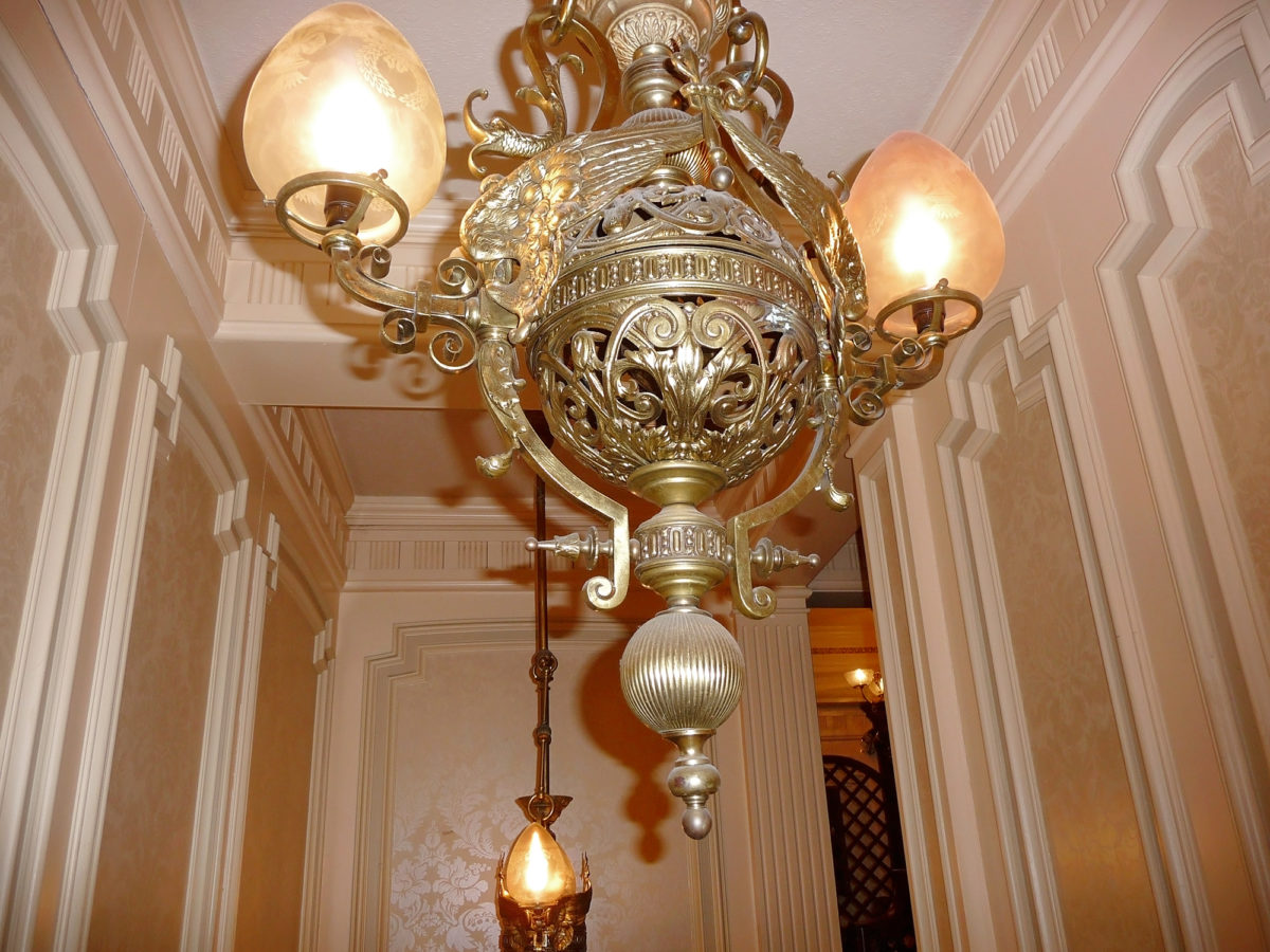 Image shows one of the gold ornate chandelier lights in Walt's restaurant, disneyland paris. 