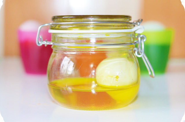 Submerging white chicken eggs in food dye to colour them. Image shows a kilner type jar containing a white egg and yellow liquid.