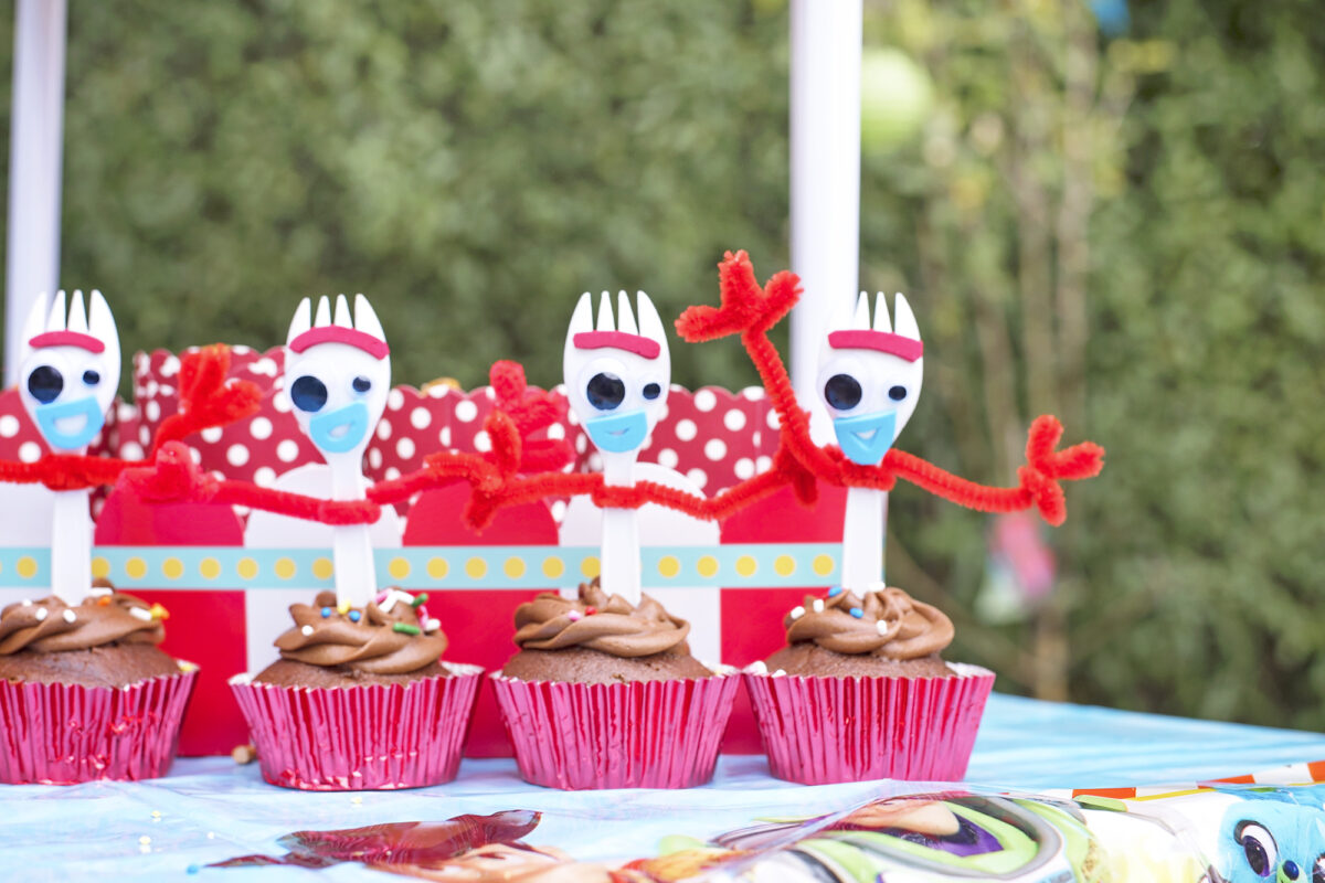 Image shows a row of Forky Cupcakes. The cupcakes are chocolate, in red foiled wrappers and each forky has been made by a DIY tutorial. 