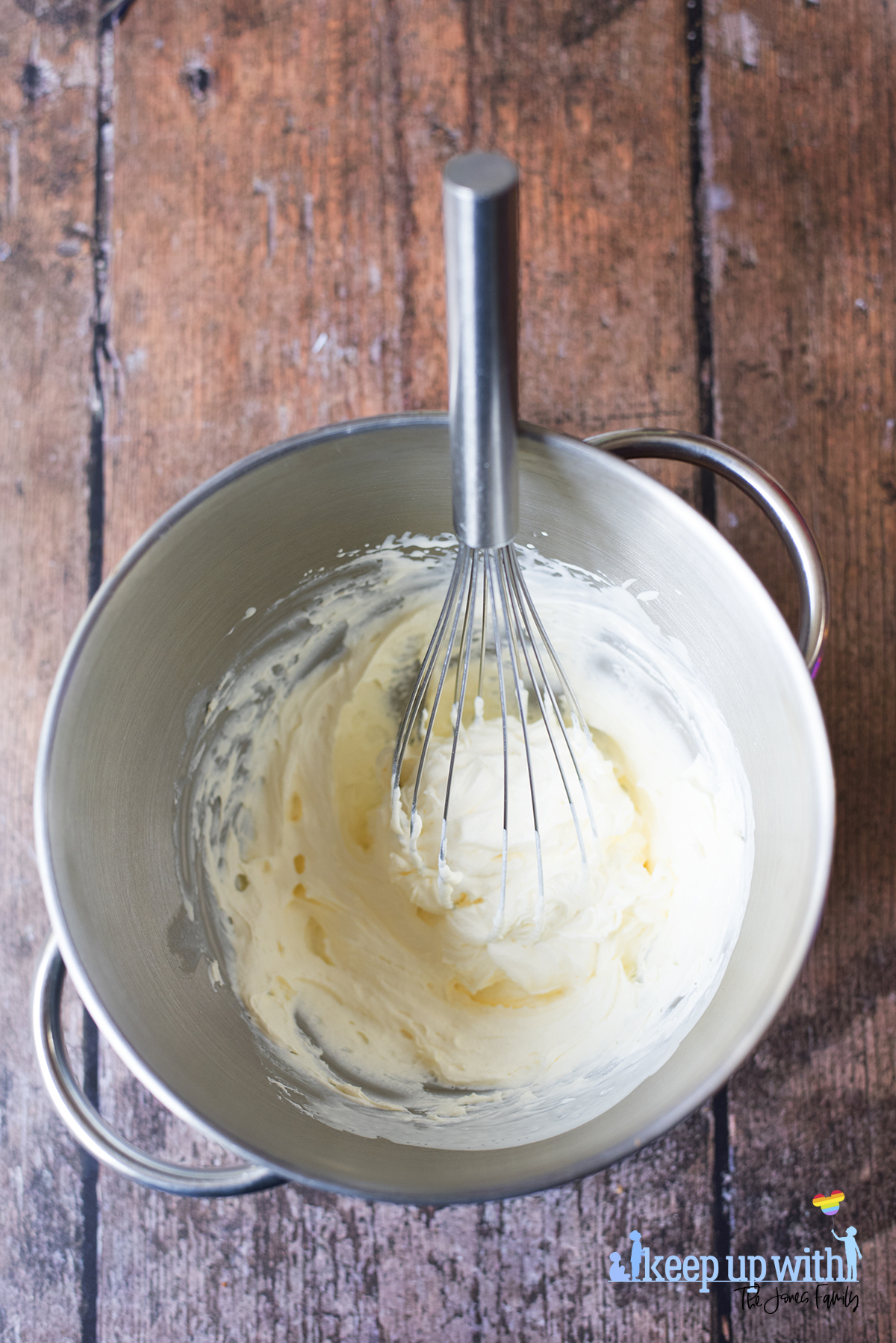 Image shows a silver mixing bowl of whipping cream ready for use, with a cream covered whisk in the bowl, on a dark wooden tabletop. Image by Sara-Jayne Jones of Keep Up With The Jones Family.