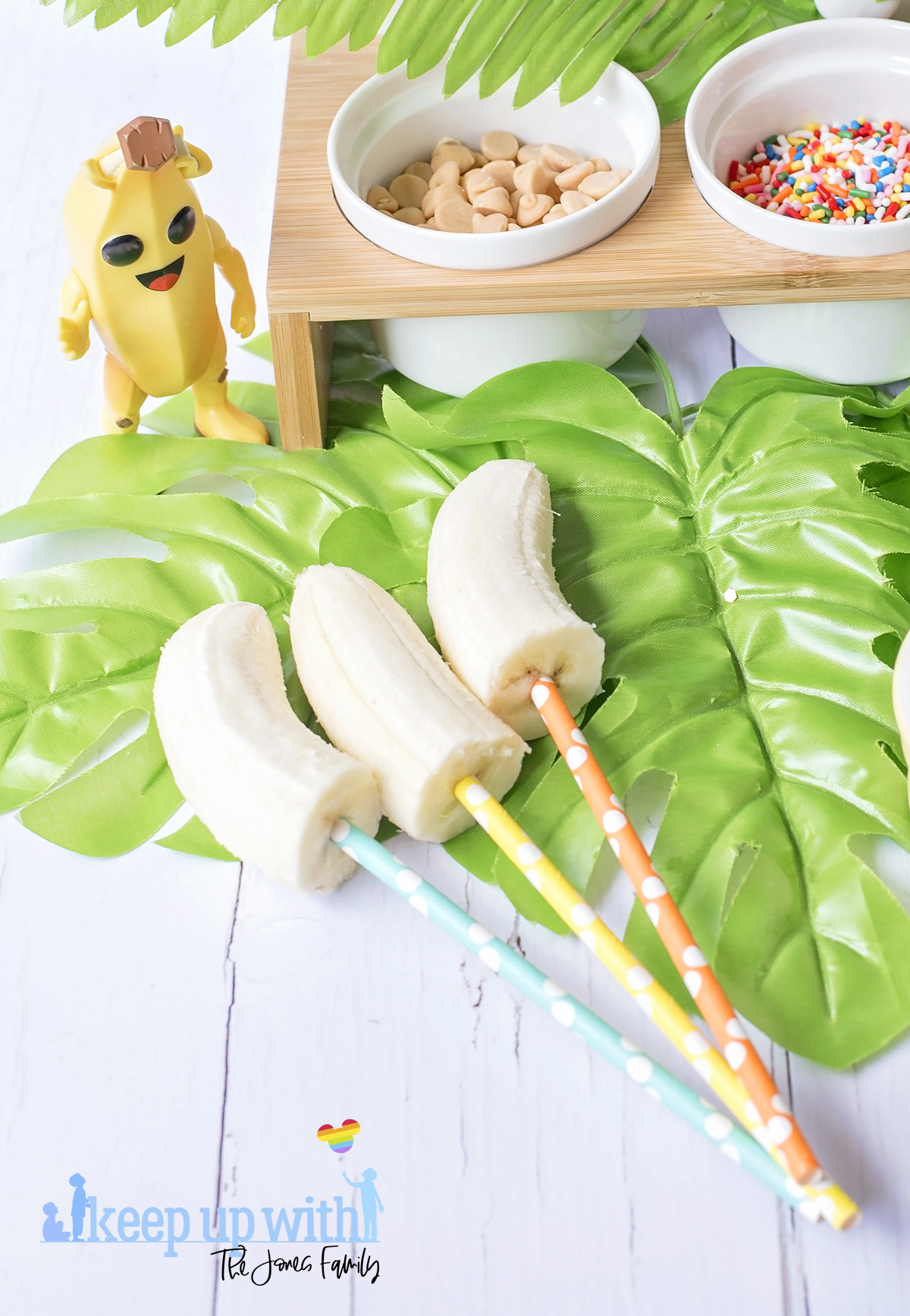Image shows Peely’s Banana Fortnite Fondue Bar, fun food for families. A Funko Pop Vinyl Peely stands on a fondue bar next to bananas on spotted coloured straws. Image by Sara-Jayne from Keep Up With The Jones Family.