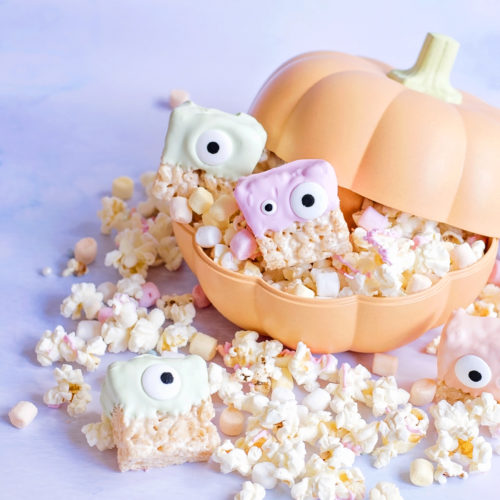 Image shows pastel coloured fun food rice krispie aliens or rice krispie monsters sat in a big orange pumpkin container filled with popcorn, which is spilling out. Image by Sara-Jayne from Keep Up With The Jones Family.