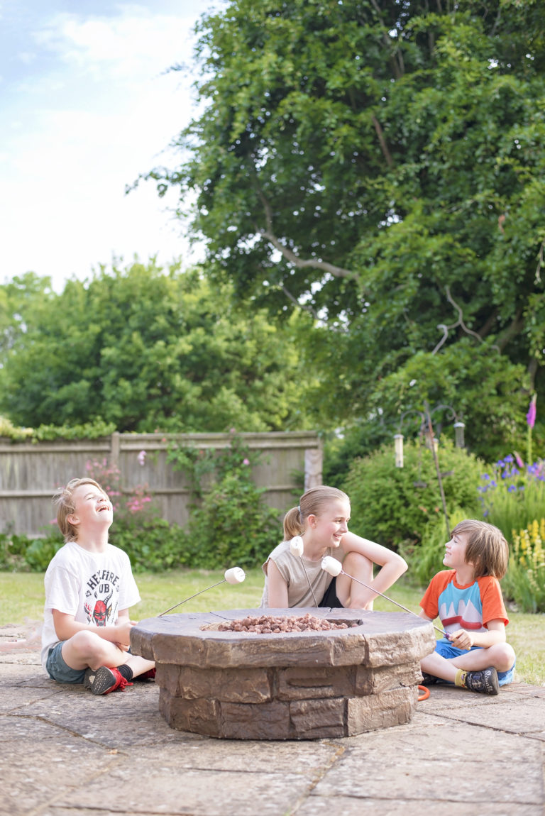 Boys around a resin firepit from very.co.uk with marshmallows on sticks making s'mores